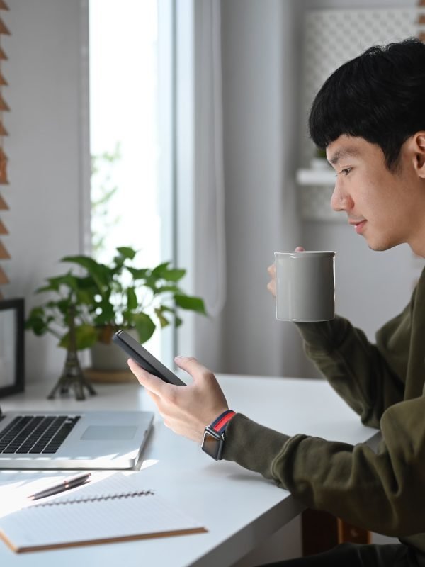 side-view-of-young-businessman-drinking-coffee-an-checking-social-media-on-mobile-phone-.jpg